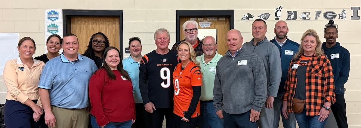 Two young students sitting next to each other with Burrow Bags on their backs filled with fresh produce