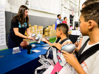 GS_0278 Elite Training Academy volunteer giving kids football toys at The Joe Burrow Foundation's second-annual Burreaux's Back-to-School Kickoff.