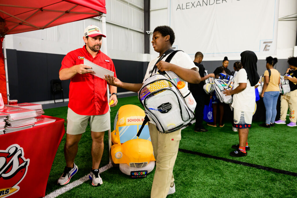 Raising Canes CEO at the Raising Canes booth handing out school supplies to kids at The Joe Burrow Foundation's second-annual Burreaux's Back-to-School Kickoff.