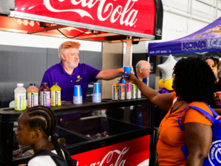 GS_0308 Volunteer handing out Body Armor drinks at a drink cart to attendees of The Joe Burrow Foundation's second-annual Burreaux's Back-to-School Kickoff.